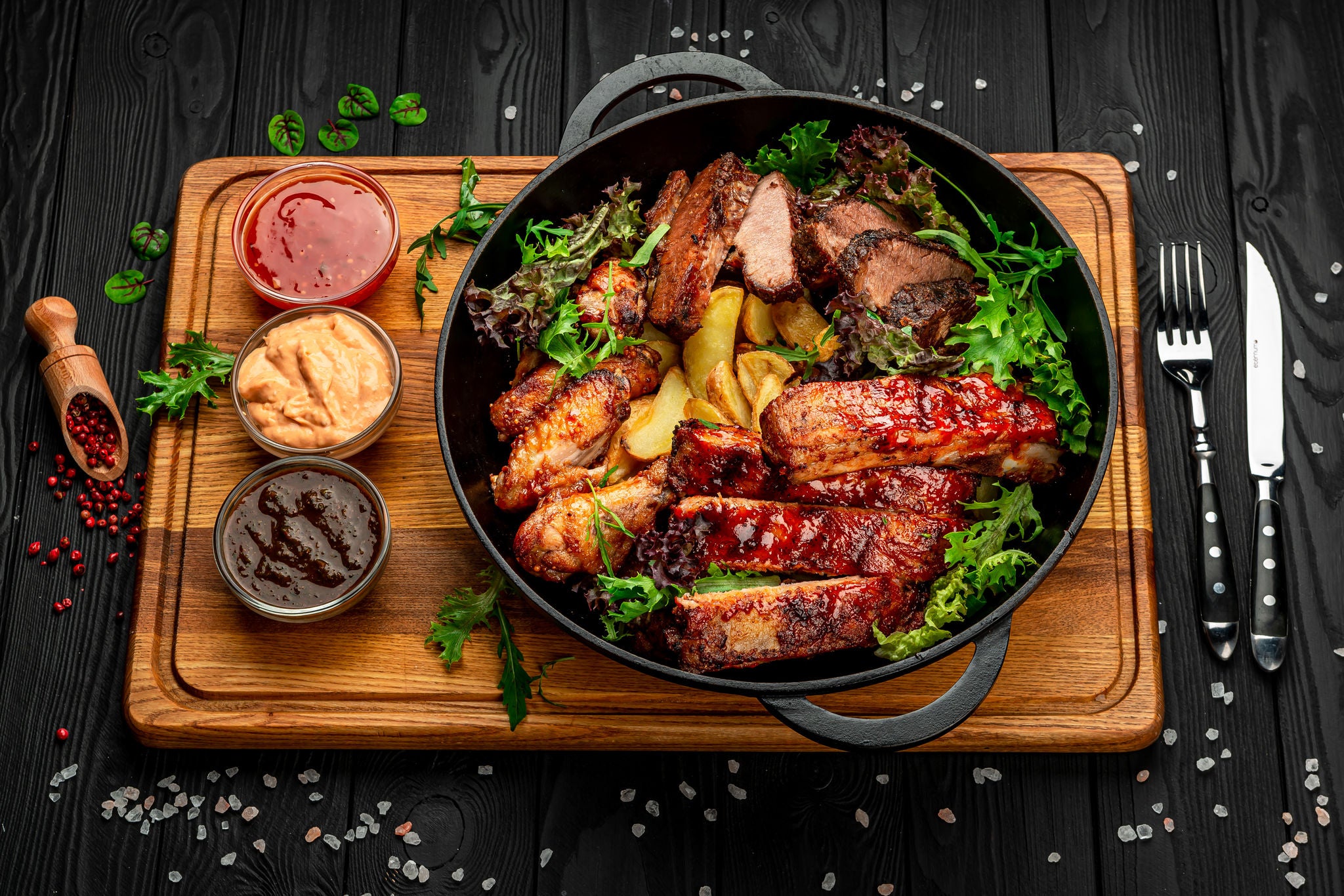 Different barbecue meat with potatoes in a frying pan